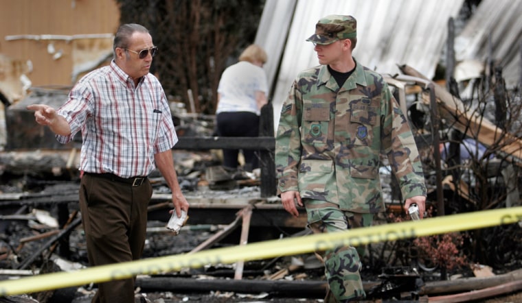 Bill Gallagher, left, shows a member of the Air National Guard the rubble of his home in the Brighton at Barnegat mobile home park in Barnegat Township, N.J., on Thursday. Gallagher lost his home to a forest fire apparently started by a flare dropped from an F-16 training at the nearby Warren Grove Gunnery Range.