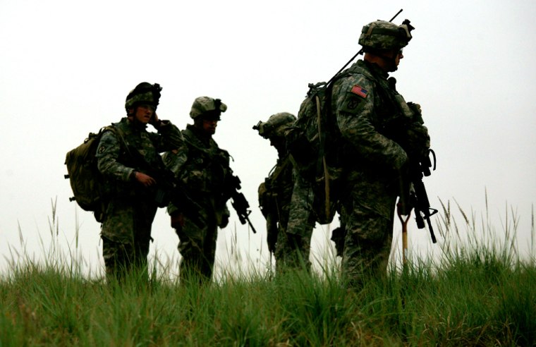 Soldiers from 2nd Platoon, Delta Company, 4th Battalion, 31st Infantry Regiment, 2nd Brigade, 10th Mountain Division, stand on a berm above a field Friday as they search for three comrades missing after a May 12 attack that left four U.S. soldiers and an Iraqi soldier dead in Quarghuli village, near Youssifiyah, Iraq.
