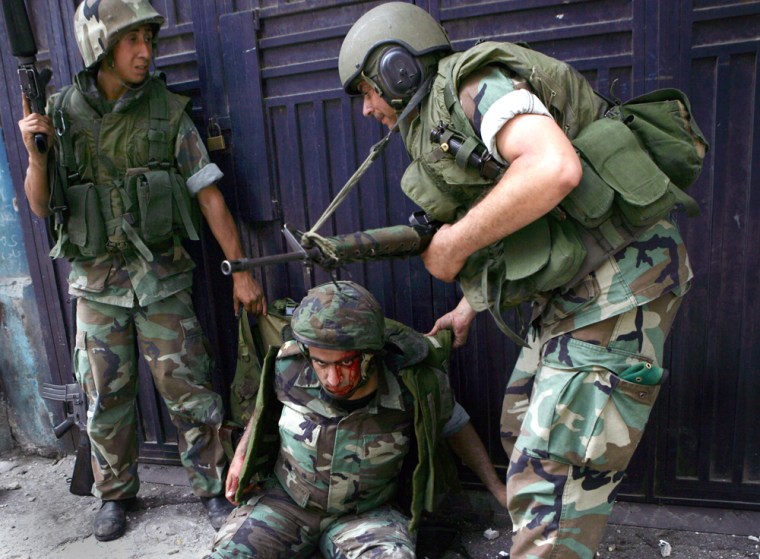 An wounded Lebanese soldier on the ground receives help from his colleagues after he was injured in clashes with fighters from an Islam militant group, in the north city of Tripoli, Sunday May 20, 2007. Lebanese security forces fought Islamic militants in the northern city of Tripoli and an adjacent Palestinian refugee camp early Sunday, in clashes that left 13 soldiers and 17 militants dead and wounded dozens. (AP Photo)