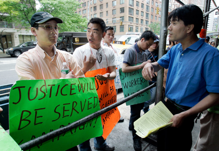 Informational picketers Chen Tianyun, left, and Zhong Guo Wu, right, talk outside Saigon Grill on New York's Upper West Side. Chen was part of a group of deliverymen who sued for back wages and were subsequently fired. His average wage, he said, was $1.81 an hour.