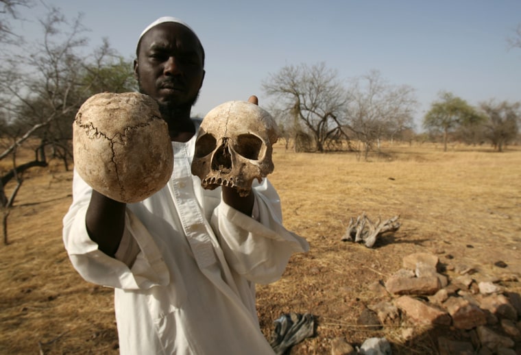Sudanese Darfur survivor Ibrahim holds human skulls at the site of a mass grave on the outskirts of the West Darfur town of Mukjar, Sudan, on Wednesday.