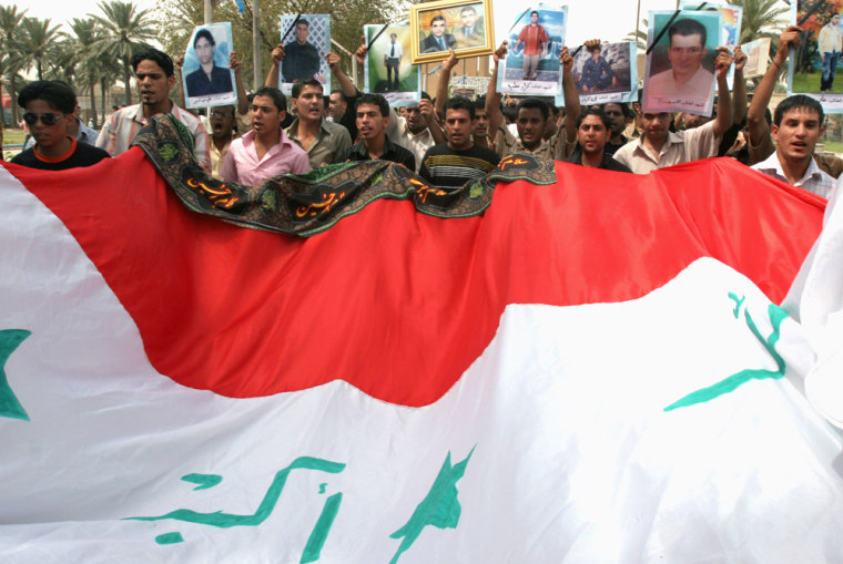 Students of Mustansiriyah university protest behind an Iraqi flag as they hold pictures of colleagues killed last week by gunmen in Waziriya neighborhood in northern Baghdad, Sunday, May 27, 2007. On May 22 a fake checkpoint by gunmen disguised as soldiers stopped a bus transporting university students, killing eight and wounding three. The demonstrators demanded the government supply protection for college and school students and move the college of education to a more secure region.(AP Photo/Karim Kadim)