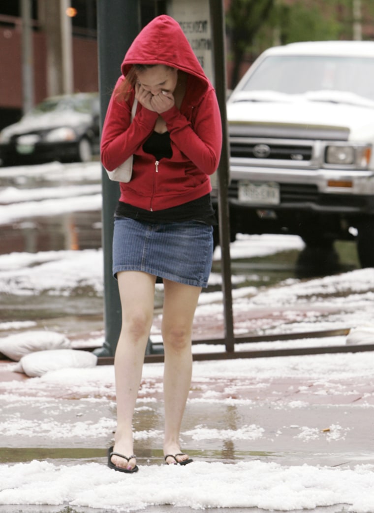 A woman wearing flip-flops walks through a pile of hail after a storm in downtown Denver on Tuesday afternoon.