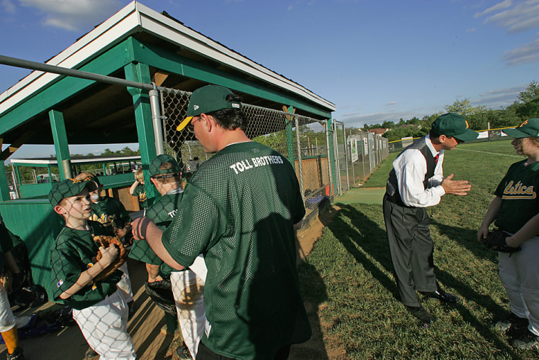 Coaches for the Athletics talk with the team during their game against the White Sox. On left in team shirt, Assistant Coach Dan Sutherland. On right, still is his work clothes, Head Coach Andrew M. Braumann. 