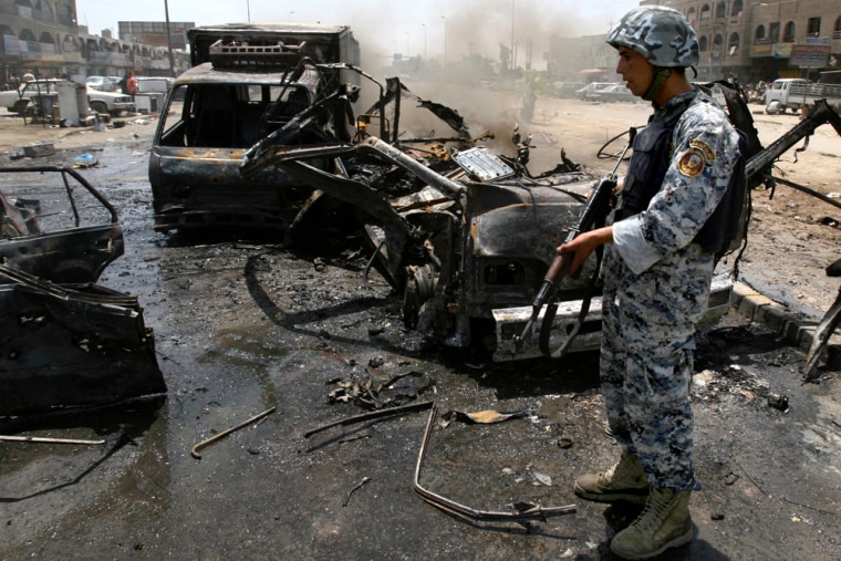 An Iraqi policeman stands beside vehicles destroyed after a bomb placed under a parked car exploded Thursday outside a restaurant in the Shiite enclave of Sadr City in Baghdad, Iraq, police said.