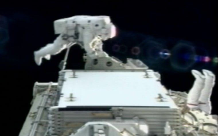 Spacewalker Danny Olivas works to connect a new power-producing segment on the international space station on Monday. The feet of fellow spacewalker James Reilly can be seen sticking up on the right side of the image.