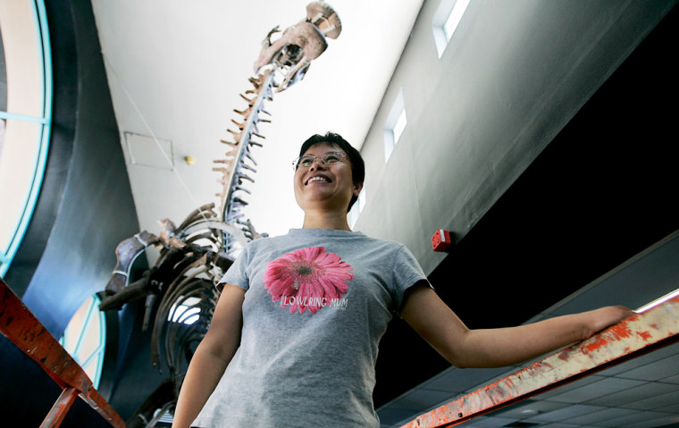 Wei Mingrui, the head of paleontology at the Beijing Museum of Natural History, poses for photo under one of the Chinese dinosaurs on display at the Miami Science Museum. Several of the dinosaurs are feathered and winged creatures whose discoveries helped firm hypotheses on the origin of birds. 