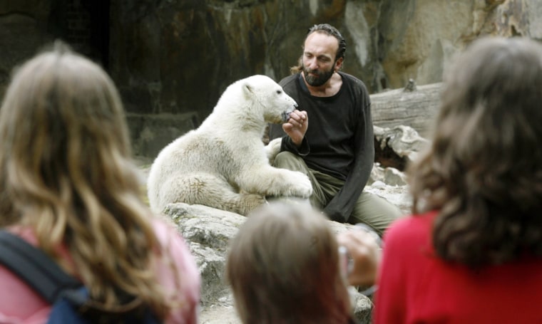 Young visitors watch polar bear cub Knut playing with employee Doerflein at an enclosure in Berlin zoo