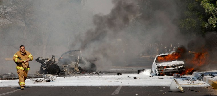A firefighter walks past burning cars after a cargo plane crashed into them in Culiacan in Mexico's state of Sinaloa