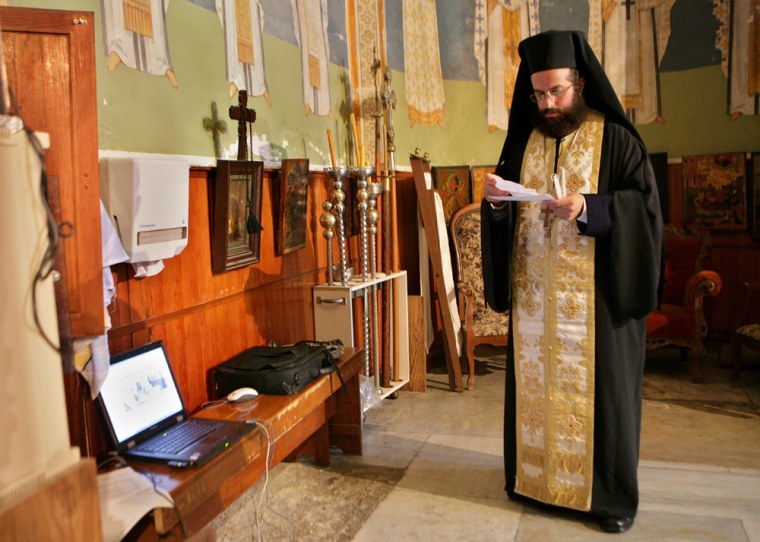Greek orthodox priest Andreas Elime prays near a laptop computer in the Basilica of the Annunciation in the northern Israeli town of Nazareth. Christian pilgrims have long traveled to the boyhood town of Jesus to seek blessings. Now the Internet can save them the trip. 