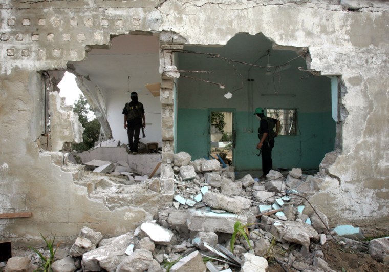 Masked Hamas gunmen check damage to a building after a military raid in the Bueij refugee camp, in the central Gaza Strip, Friday. Israeli-Palestinian fighting flared in the area, and 11 militants were killed.