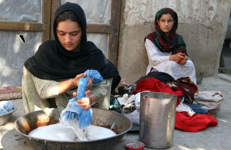 Malia, 16, washes her family's clothes as her sister watches in Jalalabad, Afghanistan, on July 1. Unable to scrounge together $165 to pay for the sheep he borrowed, Nazir Ahmad said he was forced to pay with Malia, now the fiancee of the lender's 18-year-old son.