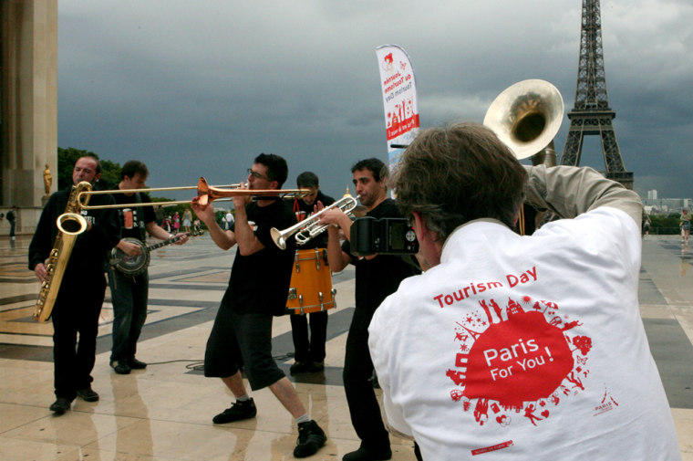 A band performs as part of the promotion of Paris Tourist Day on the Trocadero square, in front of the Eiffel Tower on July 9 in Paris. On Paris Tourist Day, city officials set out to change the grumpy reputation of Parisians, and the mayor urged tourists to "try out French products" — instead of heading to the first Starbucks in search of friendly service.