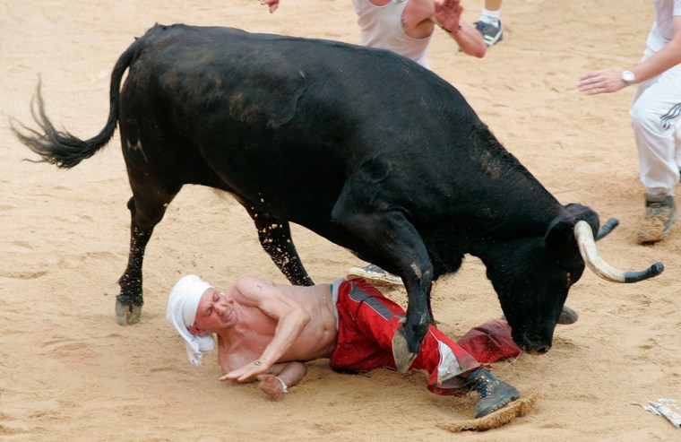 A runner is trampled by a wild cow during the first running of the bulls in Pamplona