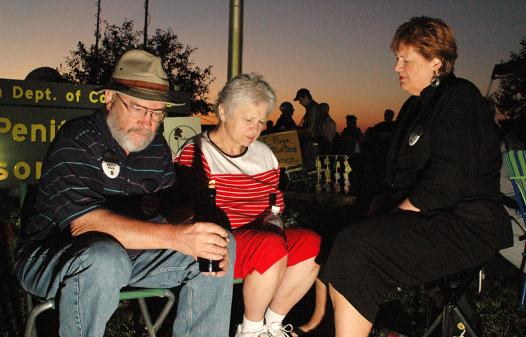 From left, Larry Schrag, Phyllis Schrag and the Rev. Susan Omansen pray by candlelight for convicted killer Elijah Page's life to be spared outside the State Penitentiary on Wednesday.