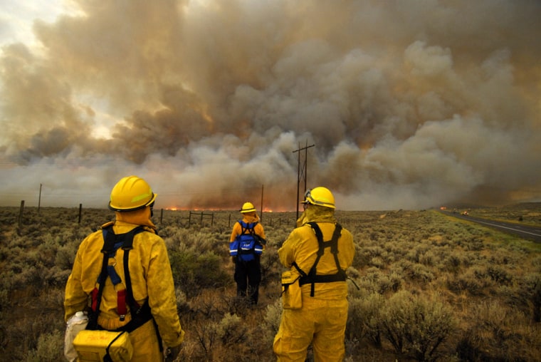 Firefighters watch the progress of the Ball's Canyon Fire as it burns toward U.S. 395 north of Reno, Nev., Tuesday.