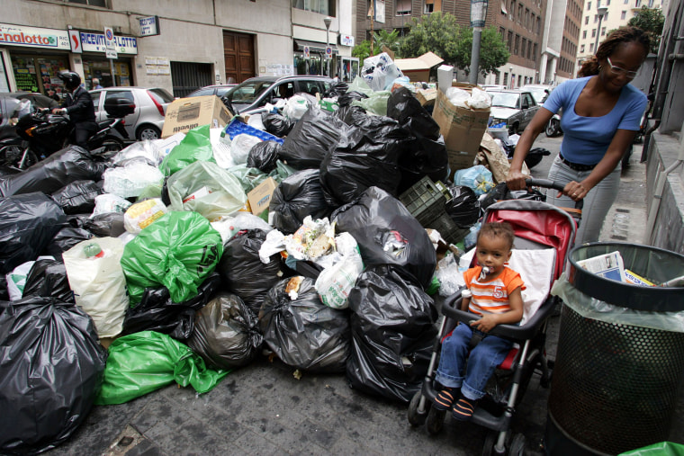A woman pushes her stroller past a heap of garbage that like several others, have piled up for more than a week in Naples, southern Italy. The U.S. Embassy in Rome has posted a message on it's Web site, warning Americans traveling to Naples and its surrounding region about possible health risks.