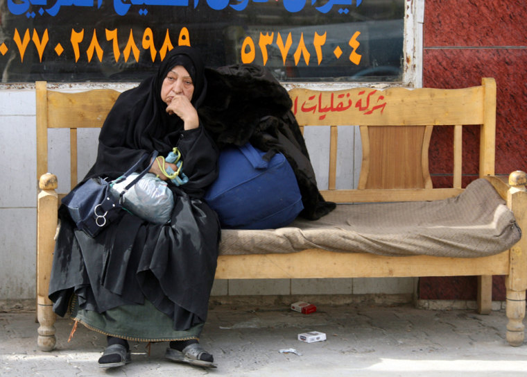 An elderly Iraqi woman waits in Baghdad for a bus that would take her to neighboring Syria.