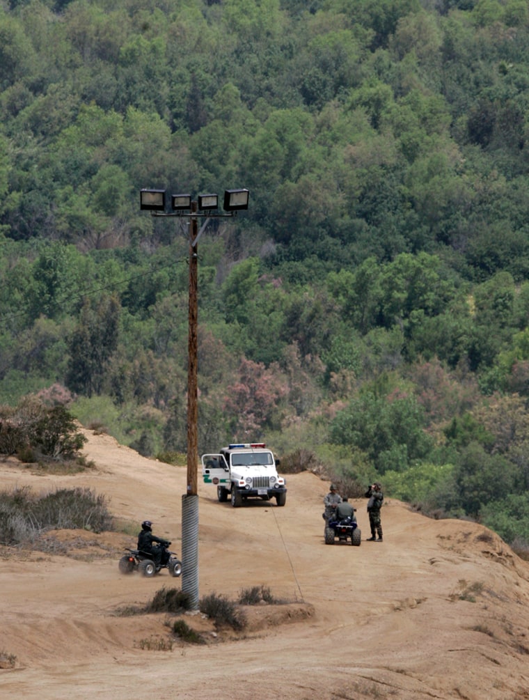 United States Border Patrol Agents watch an area between Russian Hill and Smugglers Gulch adjacent the U.S.-Mexico border Wednesday, May 30, 2007, in San Diego. The area has long been a difficult area for the Border Patrol because of the rugged terrain. The area is currently being modified by the National Guard using earth moving equipment.   The area's rugged terrain has prevented the completion of the new border fence and the maintenance of the old border fence. (AP Photo/Lenny Ignelzi)
