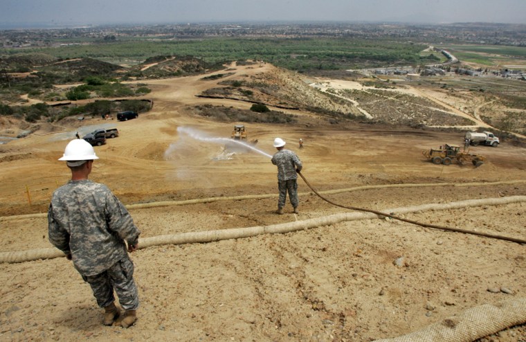 California National Guard soldiers water down areas excavated for construction of a border fence in May in the Russian Hill area adjacent to the U.S.-Mexico border in San Diego.