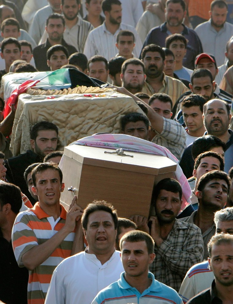 Mourners carry coffins during the funeral procession for some of those killed during a dawn raid in east Baghdad