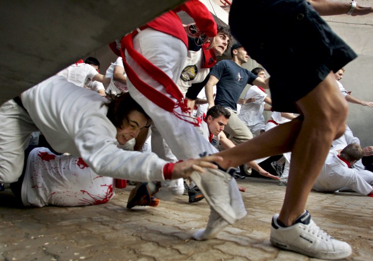 Revelers fall as they are chased by Victorino's fighting bulls during the running of the bulls at the San Fermin fiestas in Pamplona, northern Spain, on Saturday.
