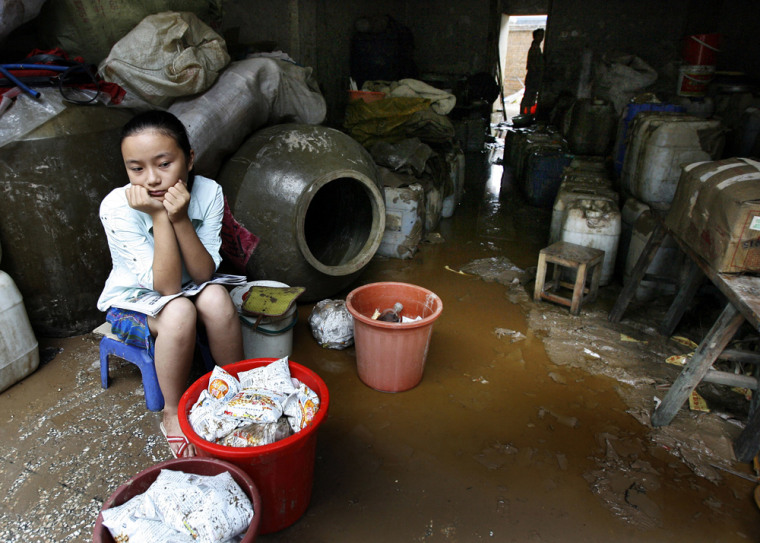 A girl sits in front of a shop in flood