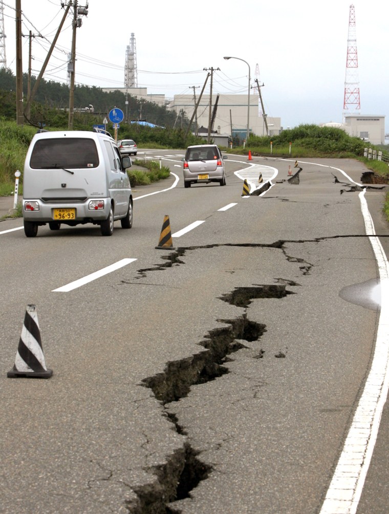 Vehicles drive on a damaged road leading