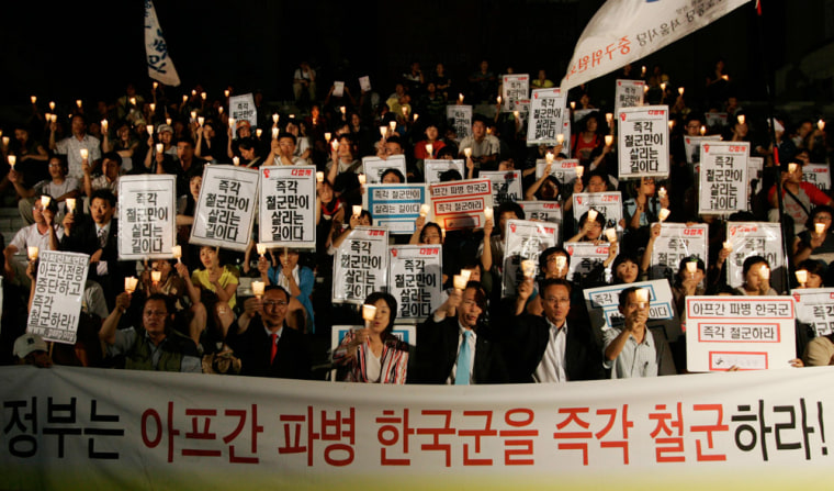 People holding candles shout slogans during candle light vigil in central Seoul