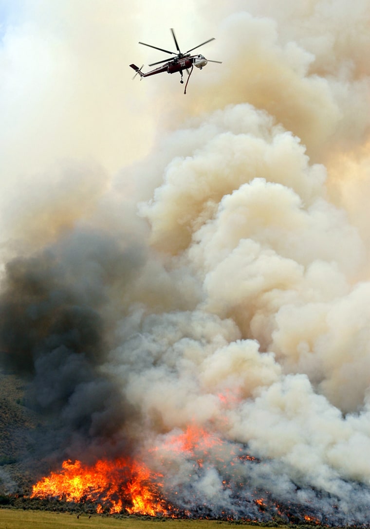 A helicopter with a water tank makes drop on the Salt Creek Fire, Sunday, July 22, 2007, near Nephi, Utah. The Sanpete County Sheriff's office briefly advised residents of Fountain Green, southeast of Nephi, to evacuate Sunday night when the wind shifted to the south, but lifted the evacuation notice when the wind shifted again. 