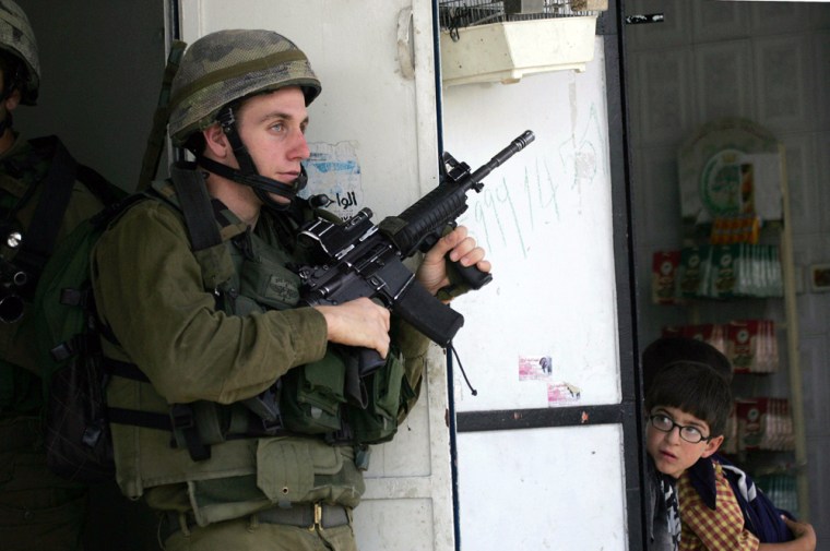 Palestinian boy looks at an Israeli soldier during a military operation in the West Bank city of Hebron