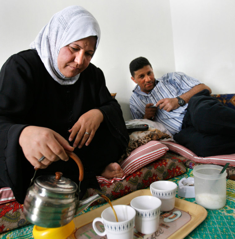 Halah Abdul Kadhum, a 42-year-old Iraqi refugee, pours tea as her brother Asaad watches at her home in Amman