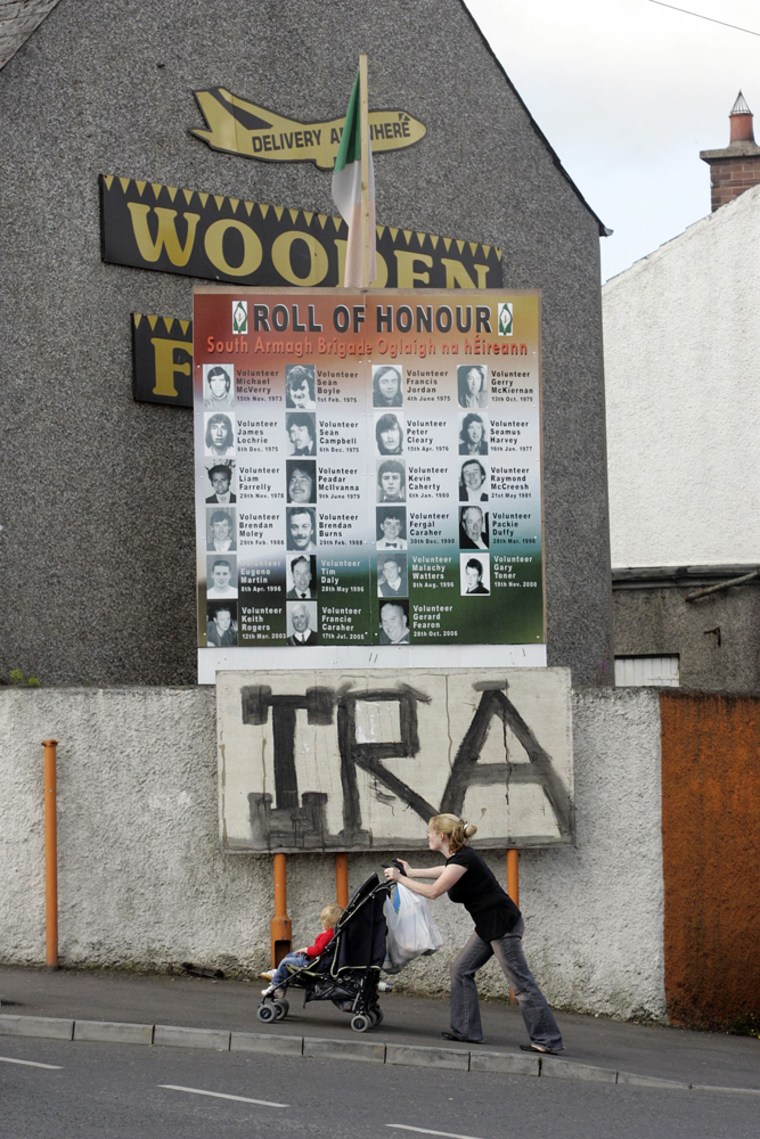 A woman and girl walk past a Republican memorial to residents of South Armagh who died during the troubles in Crossmaglen, Northern Ireland