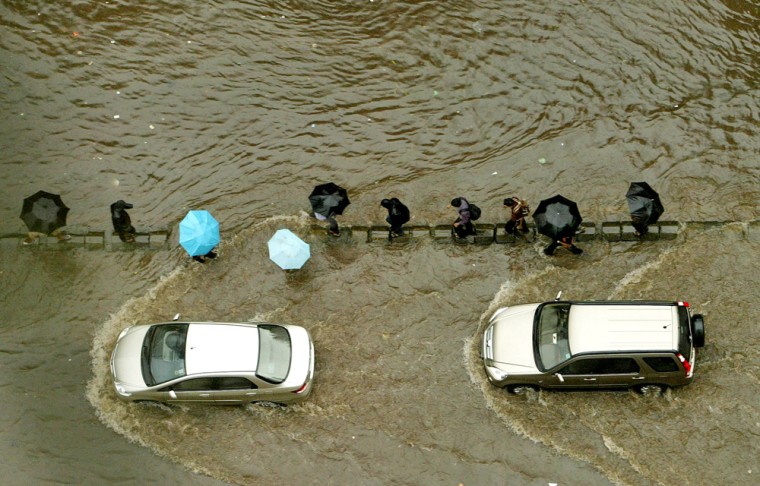 People wade through a flooded road in Mumbai, India, Friday, Aug. 3, 2007. Heavy monsoon rains and floods have killed at least 178 people and displaced another 19 million across Bangladesh and much of northern India, officials said Friday.
