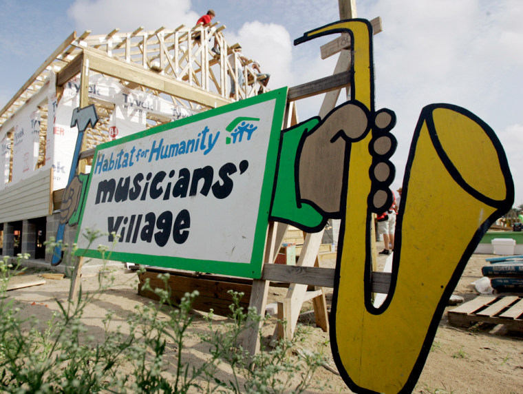 **ADVANCE FOR MONDAY, AUG. 6 ** Volunteers from Habitat for Humanity work on a home at the new Musician's Village in New Orleans, Wednesday, June 27, 2007. The tidy cluster of about 80 brightly painted homes is intended to attract musicians to stay in the city so damaged by Hurricane Katrina. (AP Photo/Eric Gay)