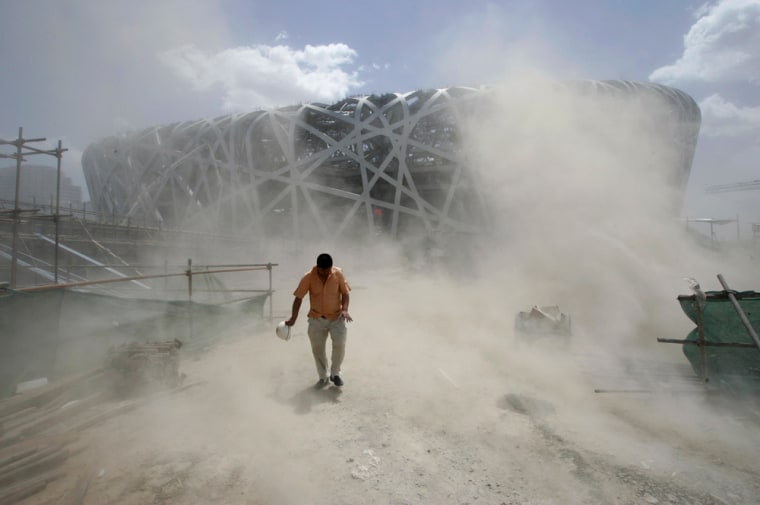 A labourer walks in the dust at the construction site of the National Olympic Stadium, also known as the 'Bird's Nest', in Beijing