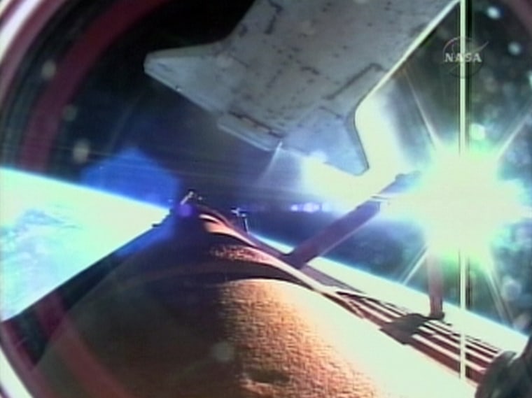The shuttle Endeavour, at top, separates from its external fuel tank during the climb to orbit, with Earth and the sun's glare shining in the background. This picture was taken by a camera mounted on the fuel tank and beamed back to NASA.