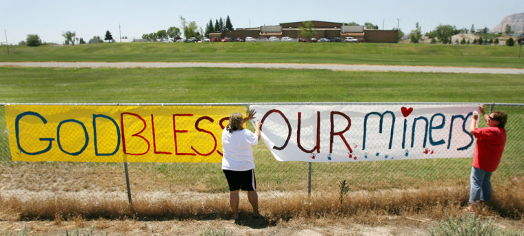 Cindy Sherman, left, and Brande Sherman put up a sign for the trapped miners and their families on the fence of Canyon View Jr. High, where the miners' families are staying during the rescue effort, in Huntington, Utah, on Tuesday.