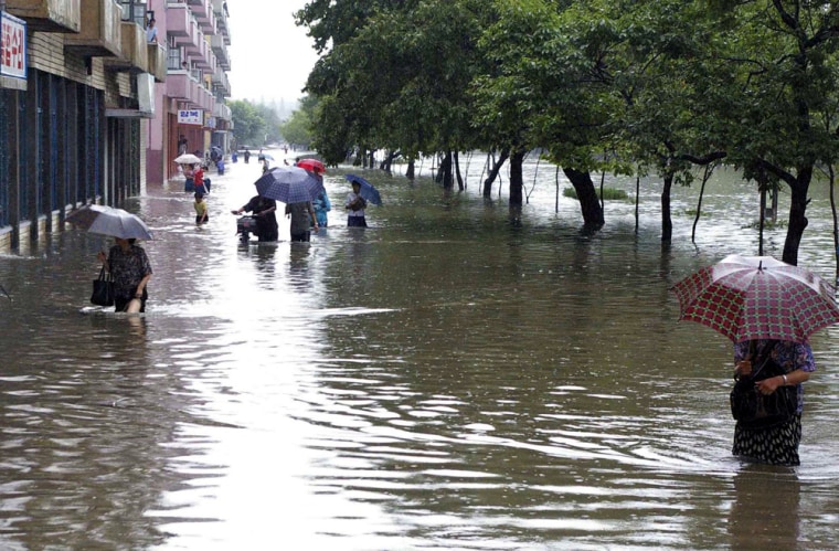 In this photo taken by Korean Central News Agency (KCNA) and released by Korea News Service, people wade through a flooded street in Pyongyang, North Korea, Saturday Aug 11, 2007. A heavy rain over the last five days caused flood and damages in North Korea, according to KCNA.