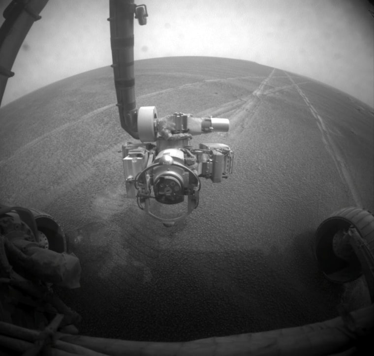 The Opportunity rover sent back this picture of its own robotic arm with Martian plains in the background on Tuesday. Dust has settled on the rover's camera lens.