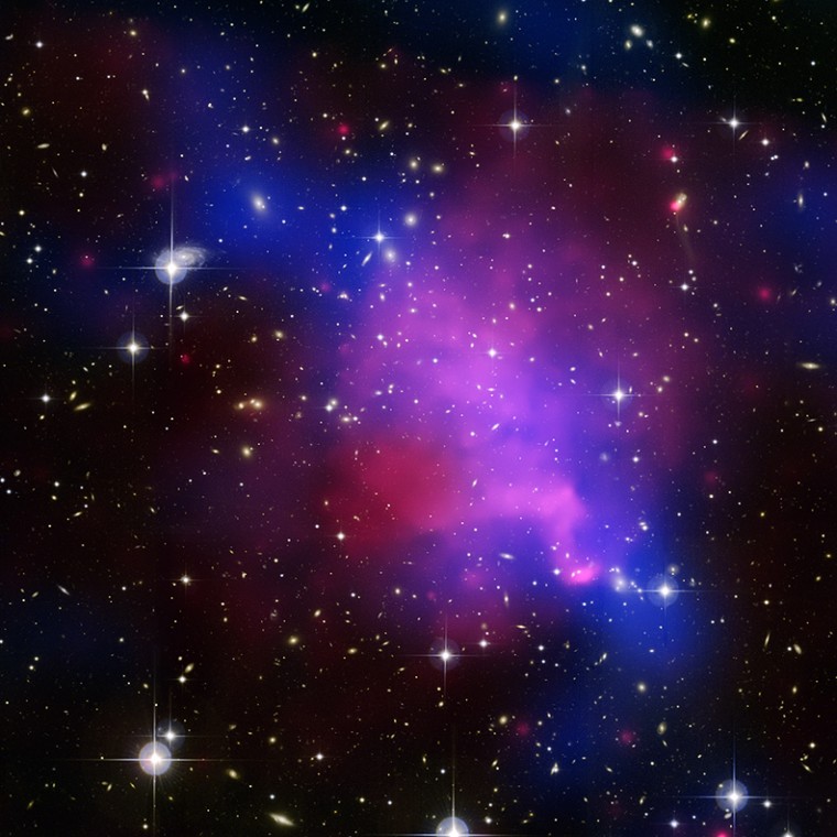 This multiwavelength image of Abell 520 shows the aftermath of a collision of galaxy clusters. In this image, the hot gas as detected by Chandra is colored red. Optical data from the Canada-France-Hawaii and Subaru telescopes shows the starlight from the individual galaxies (yellow and orange). The location of most of the dark matter in the cluster (blue) was also found using these telescopes. Scientists say the concentration of dark matter does not line up with the concentration of normal matter — which is puzzling.