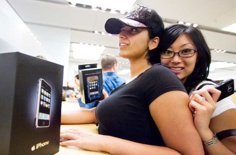 Rosa Simingalam, left, with her friend Jennifer Chang, buys an iPhone at an Apple store in Tysons Corner, Va.