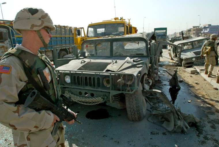 A U.S. soldier stands guard near a Humvee destroyed by an explosive device in Mosul, Iraq.