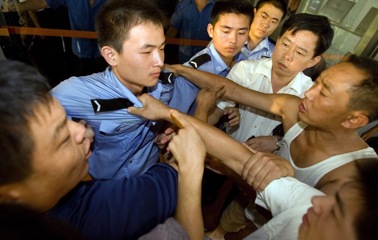 Angry relatives try to break through a security line to get into the office building of the Huayuan Mining Co. when their demands for information about their trapped relative went unmet in Xintai, eastern China's Shandong province, Monday, Aug. 20, 2007. Four days into a mine flood that trapped 181 miners, relatives remain in the dark on the progress of rescue efforts. (AP Photo/Ng Han Guan)