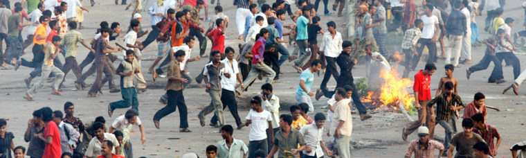 Activists run for cover as police chase them during clashes in Dhaka