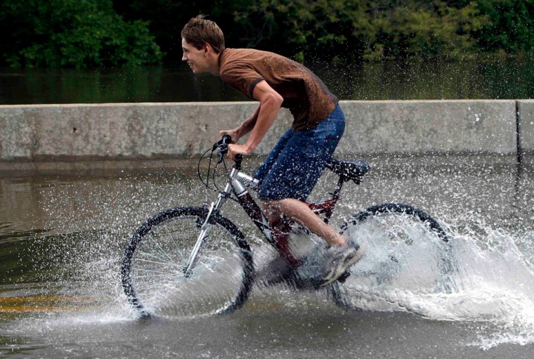 Dan Thompson rides his bike through a flooded portion of River Road in Des Plaines