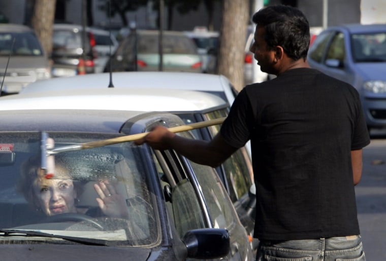 A woman in Rome signals that she doesn't want her windshield cleaned at a traffic light on Wednesday.