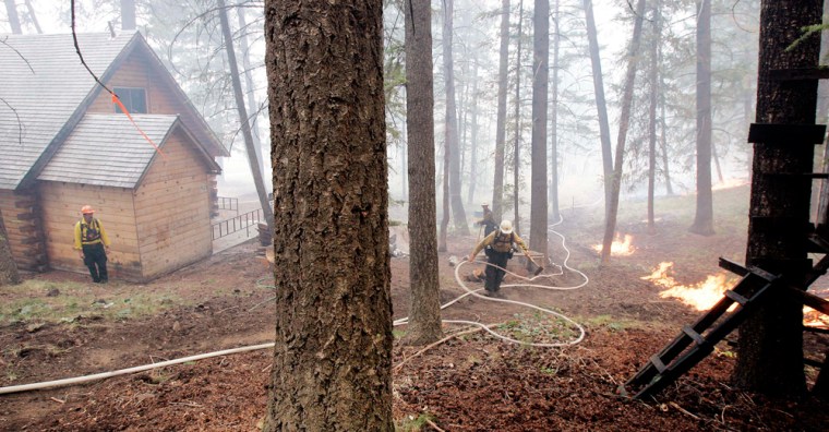 Firefighters string hose and work next to a back-burn directly behind houses to keep the main fire at bay Thursday, Aug. 30, 2007, in the Warm Springs area of Ketchum, Idaho. The Castle Rock fire has ebbed and flowed around this resort town for days, growing to 72 square miles, about three square miles bigger than Wednesday and is now 55 percent contained, compared to 49 from a day earlier. Officials are watching the weather for predicted thunderstorms that may move through the area. (AP Photo/Elaine Thompson)