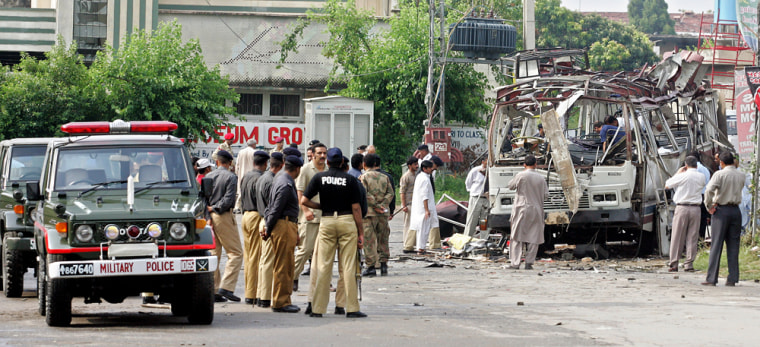 Security officials gather around a bus in Rawalpindi, Pakistan, after it was destroyed in a suicide attack on Tuesday.