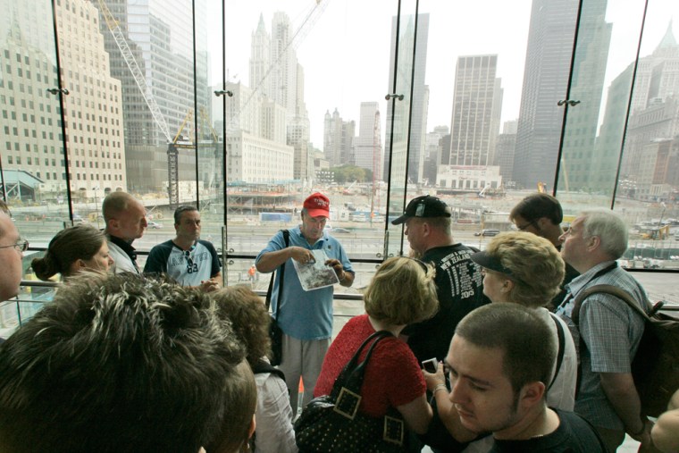 A tour guide shows photos of the terrorist attacks on the World Trade Center while talking to a group of tourists over looking Ground Zero from the World Financial Center, Monday, Sept. 10, 2007 in New York.  (AP Photo/Mary Altaffer)
